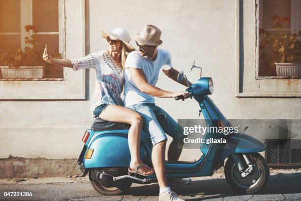 couple on a scooter bike driving through city streets. - man with scooter stock pictures, royalty-free photos & images