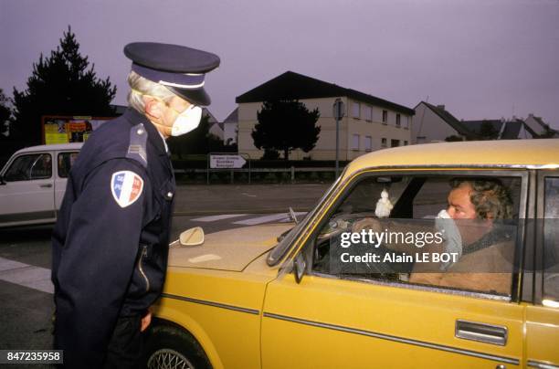Safety measures due to toxic cloud above the city ; a policeman wearing a mask on his face speaks with a car driver on October 29, 1987 in Nantes,...