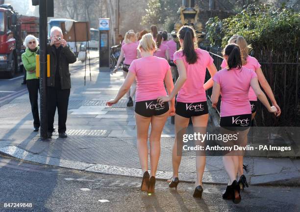 Man takes a photograph as 100 girls wearing hot pants walk across central London during the launch of Veet EasyWax's nationwide competition to search...