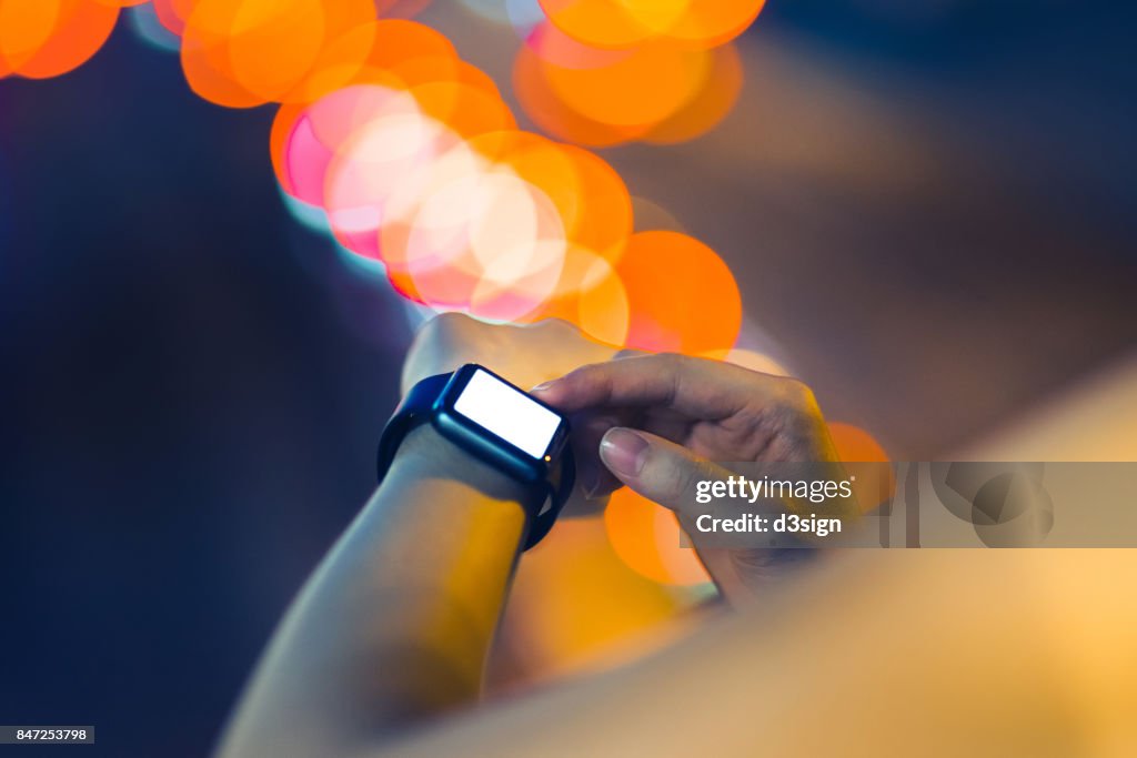 Human hands using smart watch outdoors at night