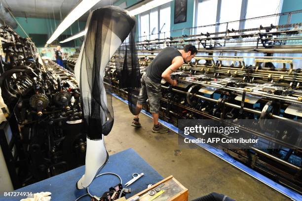 Worker on a machine manufactures silk stockings in the society of Arsoie on September 7, 2017 in Sumène in the southern France. / AFP PHOTO / Pascal...