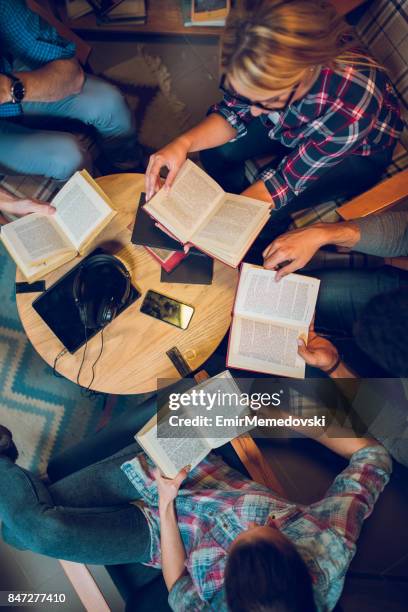 diverse group of friends discussing a book in library. - reading glasses top view stock pictures, royalty-free photos & images