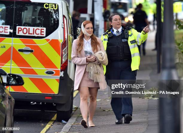 An injured woman is assisted by a police officer close to Parsons Green station in west London after an explosion on a packed London Underground...