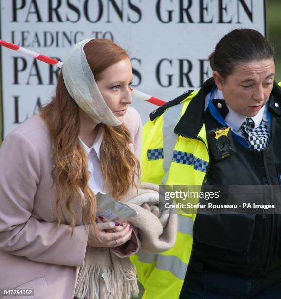 An injured woman is assisted by a police officer close to Parsons Green station in west London after Scotland Yard declared a terrorist incident...