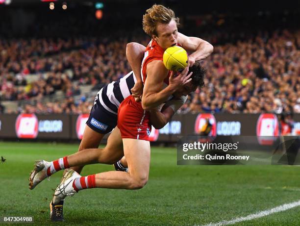 Callum Mills of the Swans handballs whilst being tackled by Steven Motlop of the Cats during the Second Semi Final AFL match between the Geelong Cats...