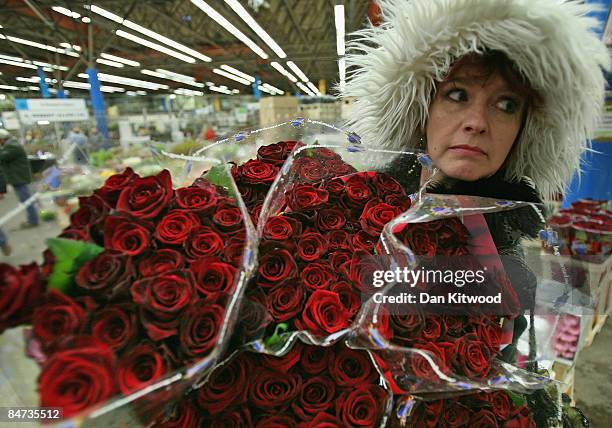 Woman carries bouquets of red roses in New Covent Garden Flower Market on February 11, 2009 in London, England. New Covent Garden Flower Market is...