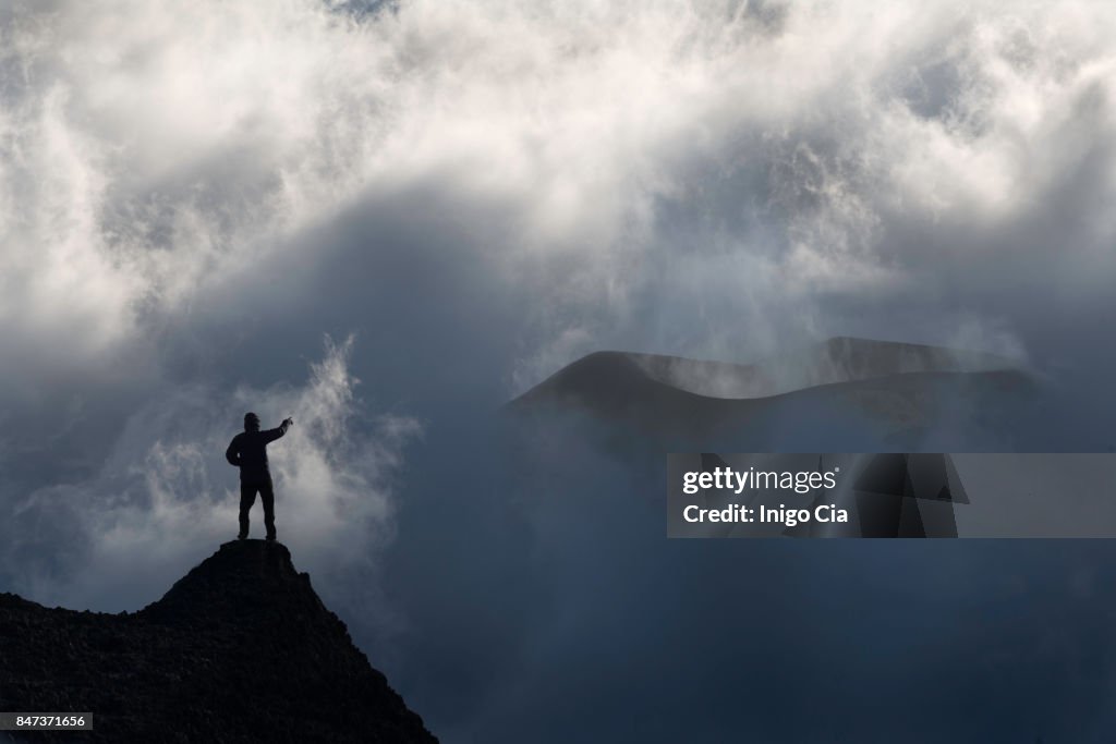 A mountanier man standing in front of a volcano