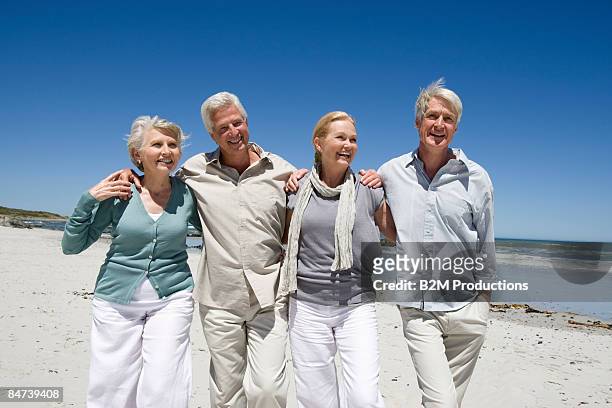 mature couple walking on beach - 55 59 anni foto e immagini stock