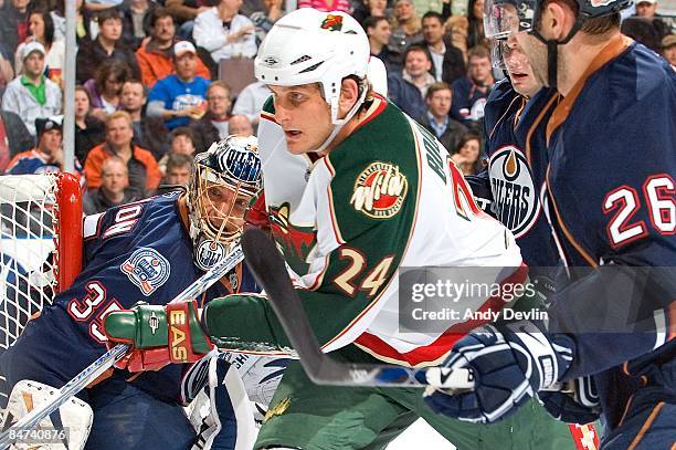 Dwayne Roloson of the Edmonton Oilers watches Derek Boogaard of the Minnesota Wild chase the puck into the corner at Rexall Place on January 30, 2009...