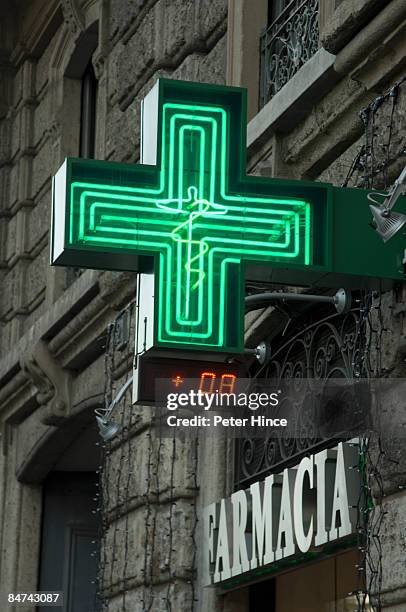 green cross sign of farmacia in milan italy - farmacia stock-fotos und bilder