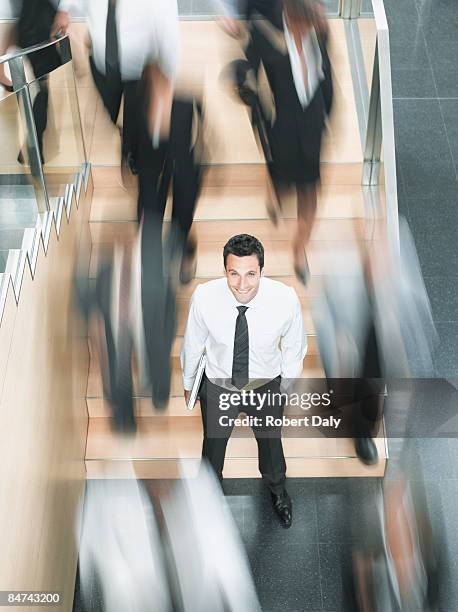 calm businessman standing in busy office - standing out from the crowd people stock pictures, royalty-free photos & images