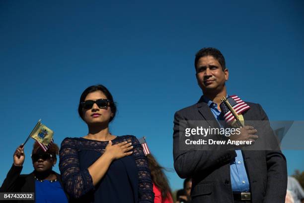 Immigrants stand for the U.S. National Anthem during a naturalization ceremony at Liberty State Park, September 15, 2017 in Jersey City, New Jersey....