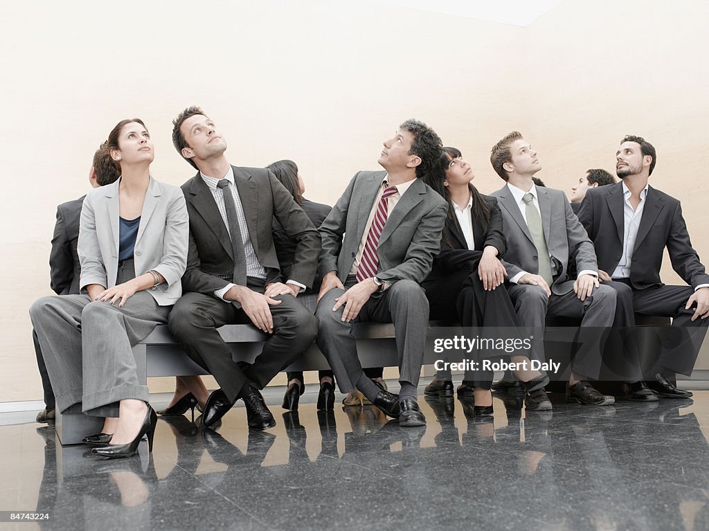 Businesspeople sitting on crowded bench