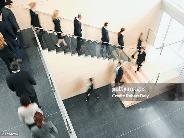 hommes d'affaires marchant vers le bas de l'escalier - uniformité photos et images de collection