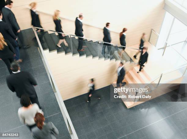 businesspeople walking down office staircase - left behind stockfoto's en -beelden