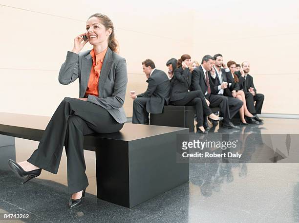 businesswoman using cell phone away from co-workers - three quarter length stock pictures, royalty-free photos & images