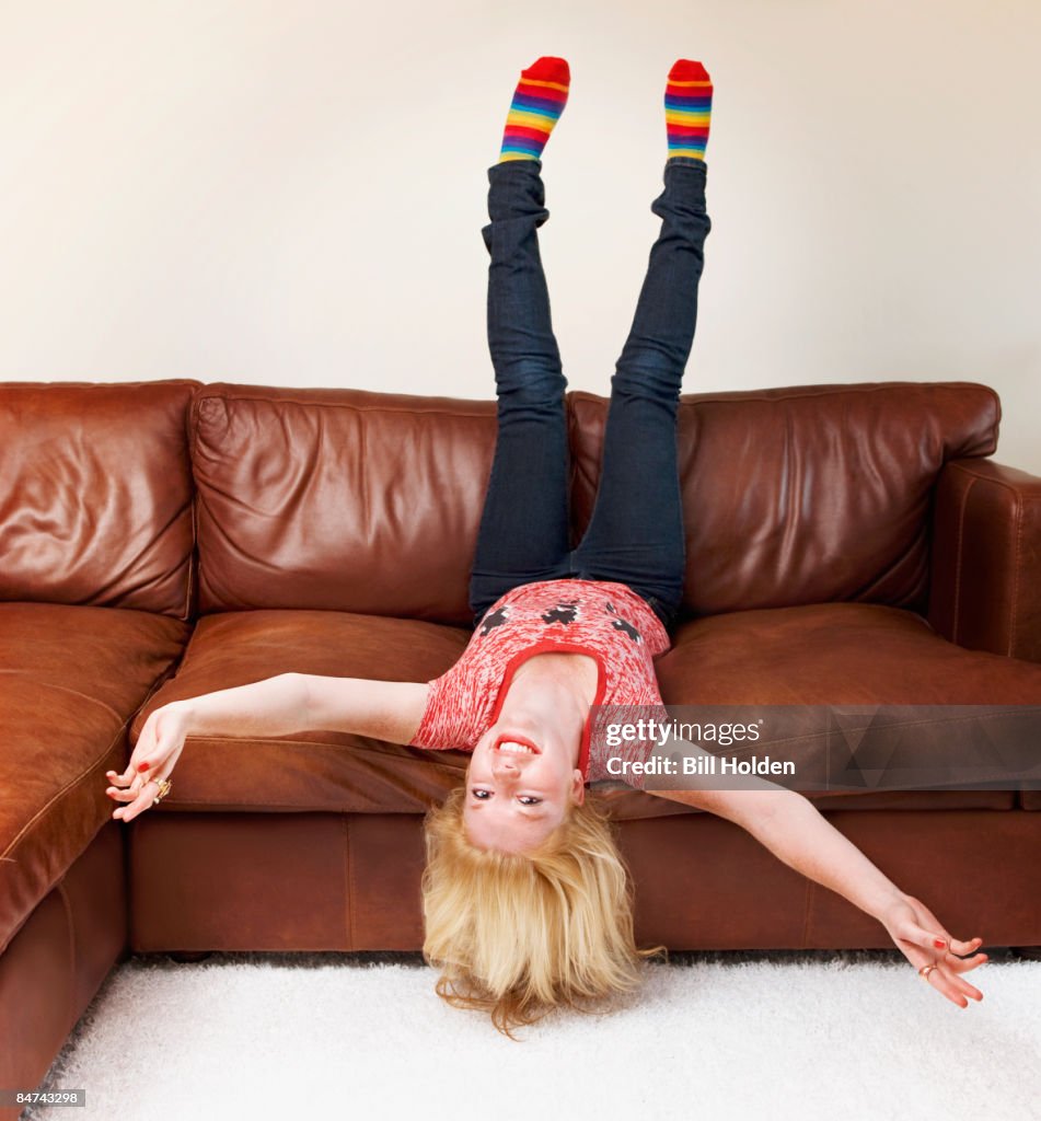 Teenage girl upside-down on sofa