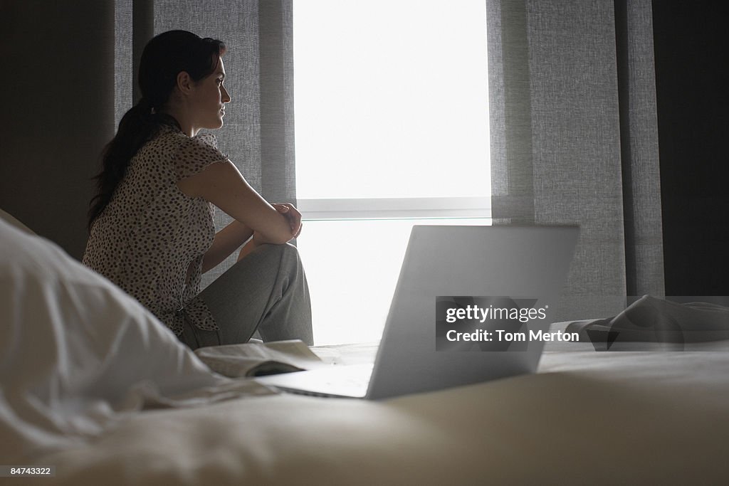 Sad woman looking out hotel window