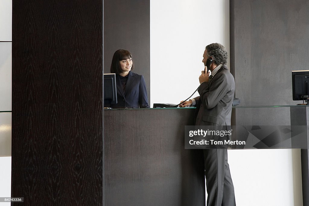 Businessman using telephone at reception desk