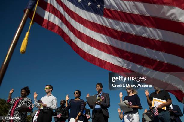 An American flag billows in the wind as immigrants stand and take the oath of allegiance to the United States during a naturalization ceremony at...