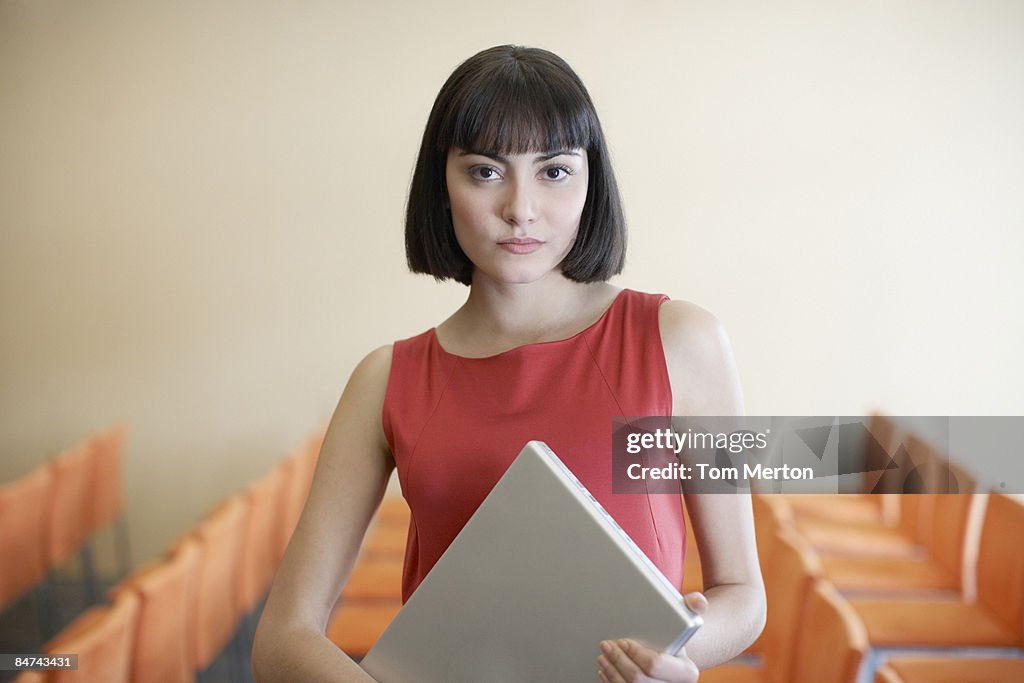 Femme d'affaires tenant un ordinateur portable dans la salle de conférence
