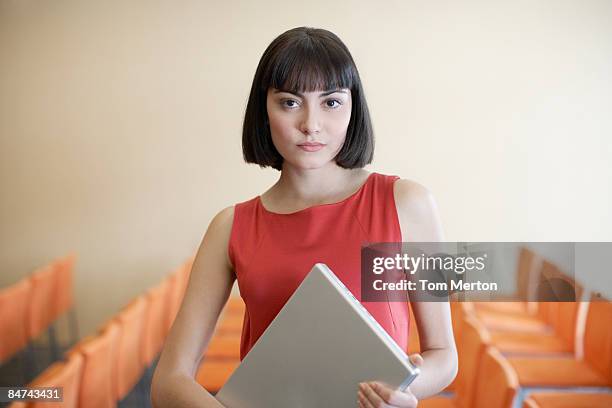 businesswoman holding laptop in conference room - red dress stock pictures, royalty-free photos & images