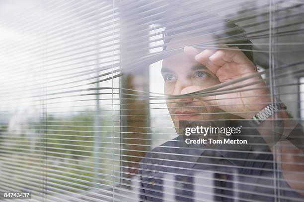 businessman staring out office window - window blinds stock pictures, royalty-free photos & images