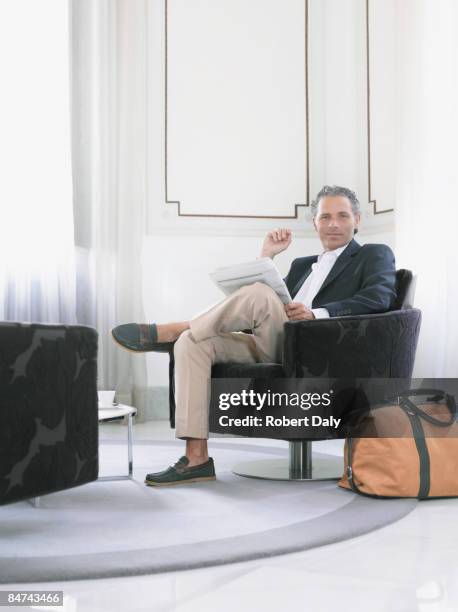 man reading newspaper in modern hotel suite  - suite stock pictures, royalty-free photos & images