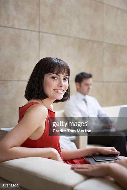 businesswoman sitting in office lobby - red dress stock pictures, royalty-free photos & images