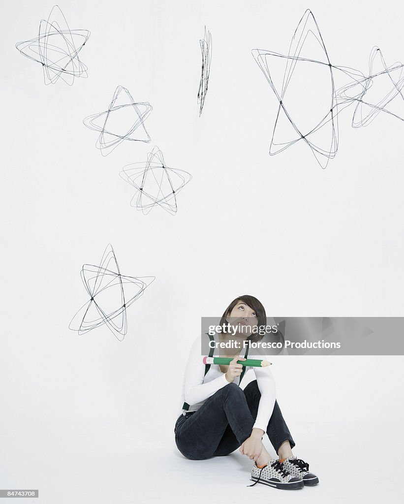 Young woman scribbling stars on wall