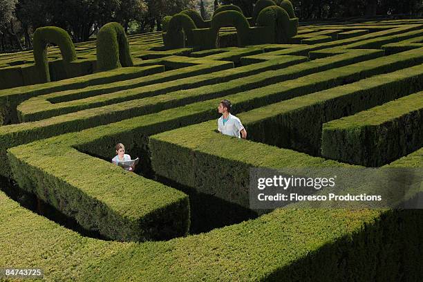 young couple lost in hedge maze - maze stock-fotos und bilder