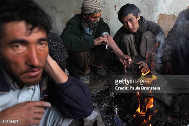 Heroin addicts inject while keeping warm by a fire inside the abandoned Russian Cultural center used as the heroin gathering point in the captiol...