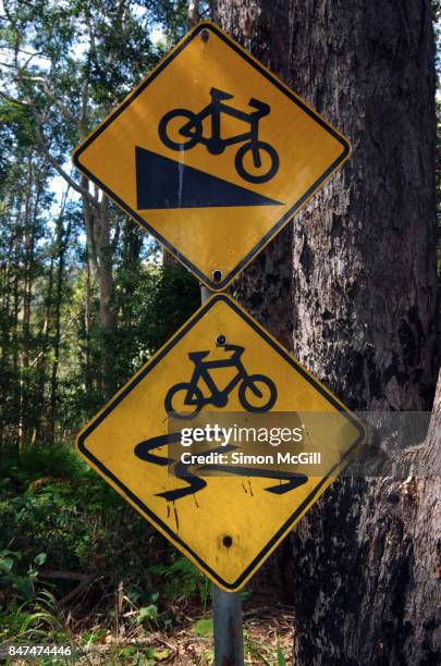 signs warning of a steep descent and a slippery cycling path in coffs harbour, new south wales, australia - varning för halka bildbanksfoton och bilder