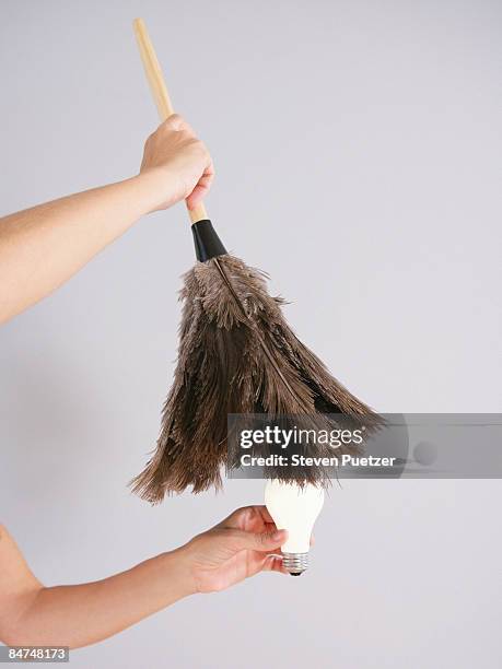 women dusting off lightbulb with feather duster - dusting off stock pictures, royalty-free photos & images