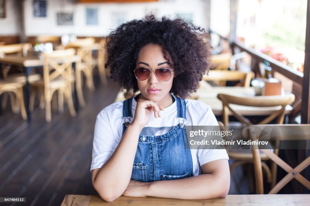 Smiling african woman sitting in sunny cafe
