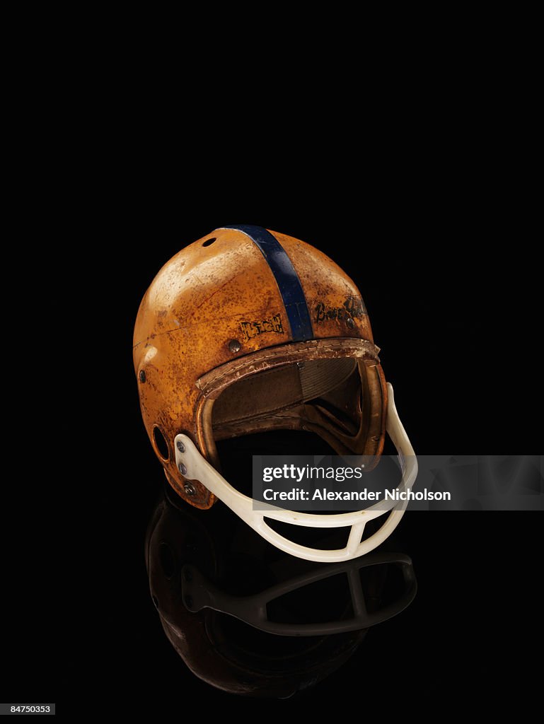 Old football helmet on black background