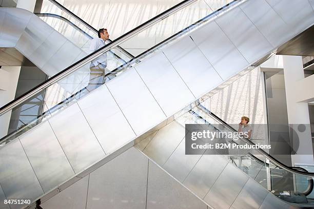business women and man on escalator - escalator stock-fotos und bilder