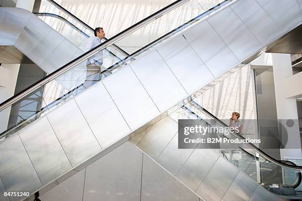 business women and man on escalator - escalator side view stock pictures, royalty-free photos & images