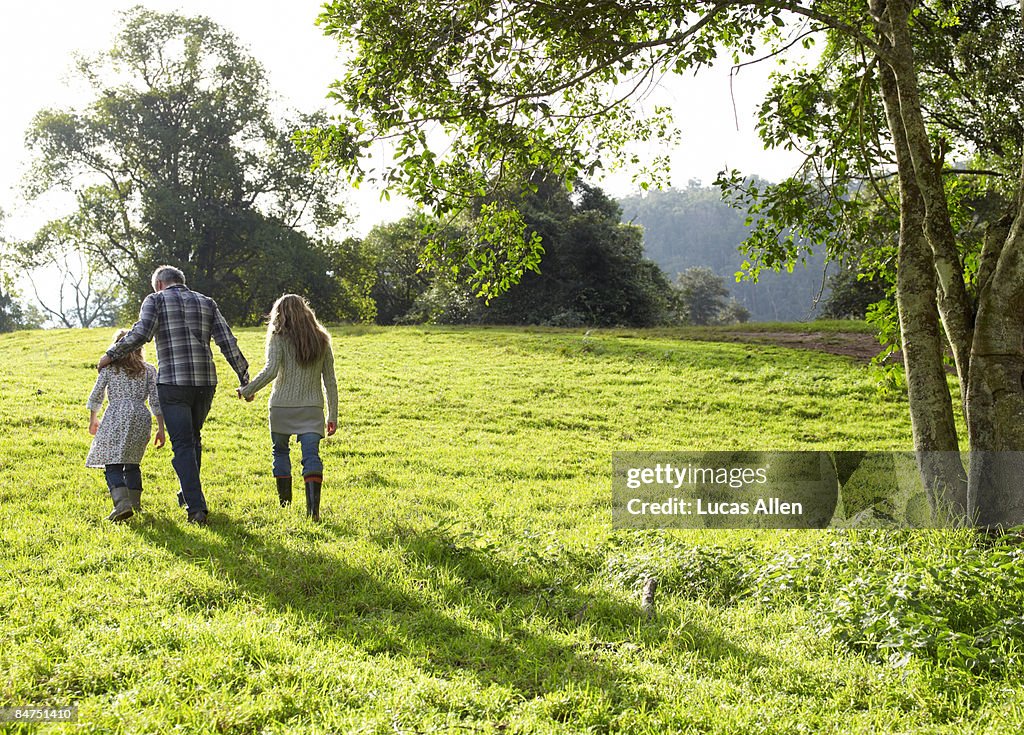 Famille à pied une colline verdoyante ensemble