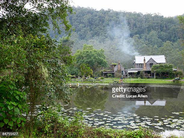 country home on a pond with smoking chimney - country new south wales stock pictures, royalty-free photos & images