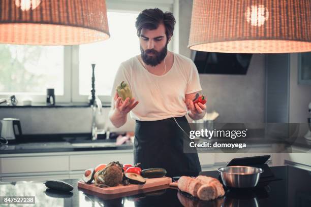 hübscher bärtigen mann kochen und anhören von musik in der küche - soup vegtables stock-fotos und bilder