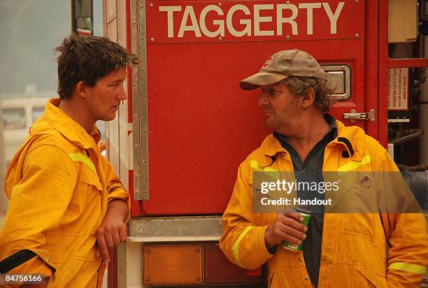 In this handout image supplied by Stephen Henderson of the County Fire Authority, Firefighters of the CFA Strike Teams chat as they rest after...