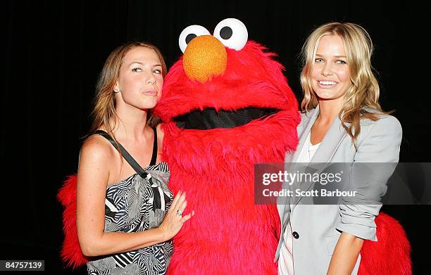 Actress Kate Ritchie and model Lara Bingle pose for a photograph with Elmo, the Muppet character from television's Sesame Street as they help raise...