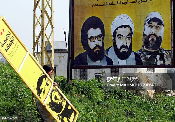 Lebanese man hangs posters of slain Lebanese Hezbollah commanders Abbas al-Mussawi , Ragheb Harb and Imad Mughnieh on the main road to the southern...