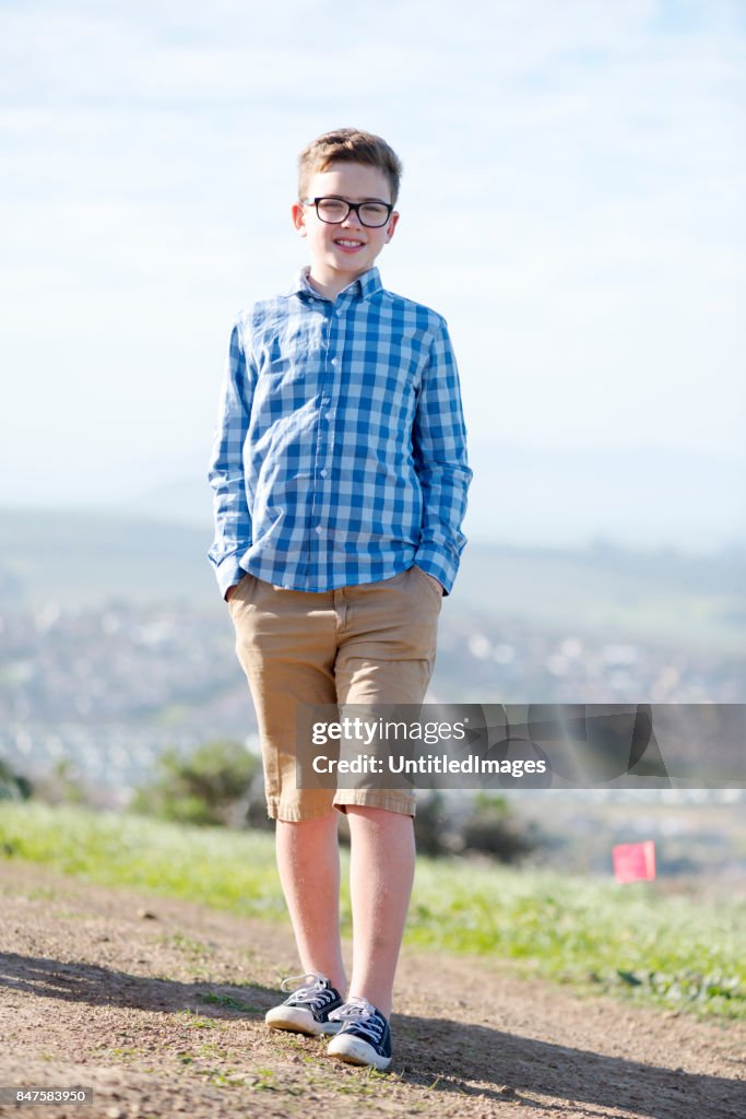 Boy with glasses standing in a footpath