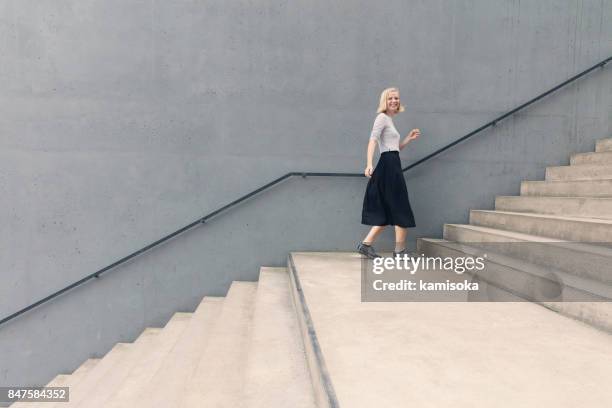 glückliche mädchen gehen auf treppen durch betonwand - fashion urban woman stock-fotos und bilder