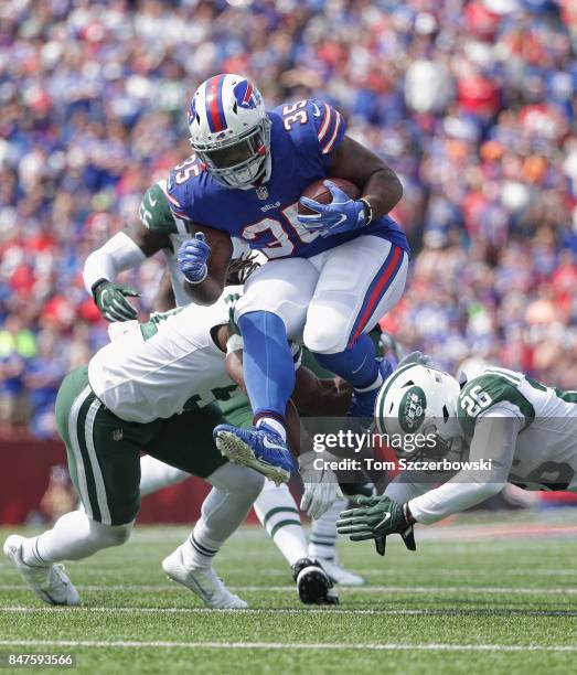 Mike Tolbert of the Buffalo Bills runs with the ball during NFL game action as he breaks a tackle by Julian Stanford of the New York Jets and Marcus...