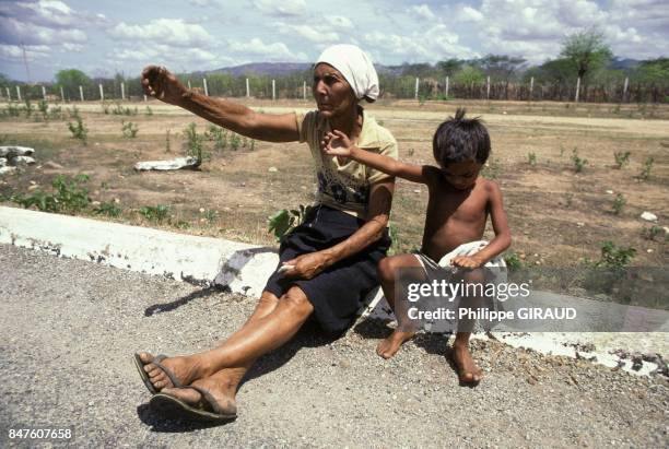 Une femme et un petit garcon assis au bord d'une route, victimes de la secheresse dans le nord-est en janvier 1984 au Bresil.