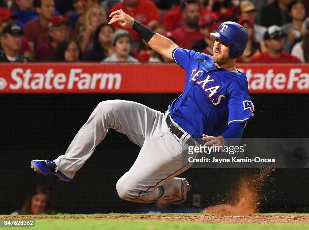 Will Middlebrooks of the Texas Rangers slides into home to score a run in the fifth inning of the game against the Los Angeles Angels of Anaheim at...