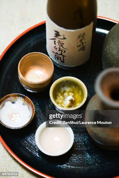 bottle of sake and sake cups on tray, close-up - sake stock-fotos und bilder